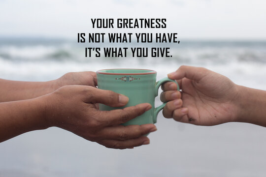 Inspirational Motivational Quote - Your Greatness Is Not What You Have. It Is What You Give. With Hands Holding Coffee Cup Showing Kindness About Take And Give On White Beach Background.