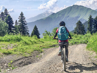 Back view of active woman riding mountain bike on road