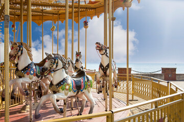 Albania, the embankment of the city of Durres. Old amusement park. Carousel with horses against the blue sky and sea. © Olena