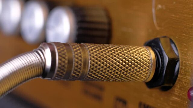 Man's hand connects audio cable to the input of professional studio device. Amplifier receiver. Plugging jack to recording equipment. Plugs instrument cable into a guitar amplifier. Macro footage.