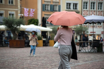 portrait on back view of girl walking in the street with orange umbrella