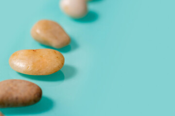 Fototapeta na wymiar 4 small brown stones, similar to pebbles, lie diagonally on the left on a turquoise background.