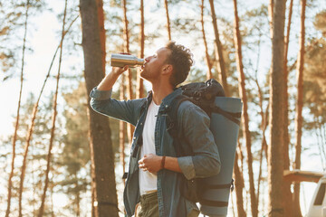 Takes a break. Man is traveling alone in the forest at daytime at summer