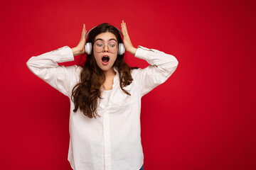 Attractive shocked young brunette female person wearing white shirt and optical glasses isolated...