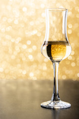 Italian golden grappa drink on yellow bright background. Copy space