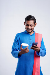 Young indian farmer using smartphone and bank card on white background.