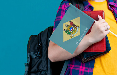 Young girl with school stuff holds in hand Delaware flag close up