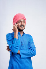 Young indian farmer talking on mobile phone over white background.