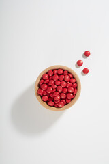 Red Chocolate Candy Pills in Bowl Isolated on White Background
