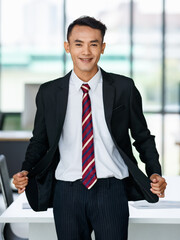 Cheerful Asian businessman standing in workplace