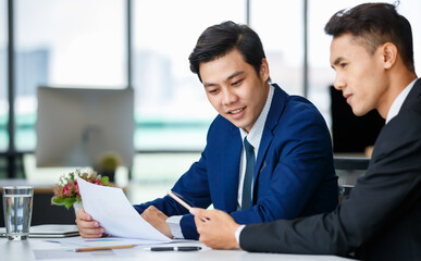 Cheerful ethnic businessmen discussing project in office