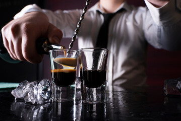 Barman preparing cocktail shots at the bar counter. Barman mixing drinks at the night club..