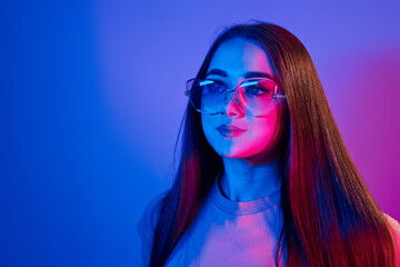 Fashionable young woman standing in the studio with neon light