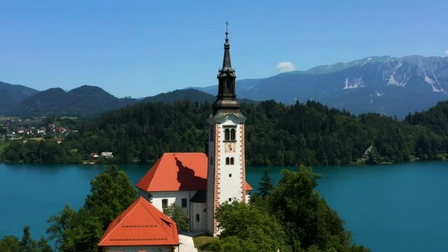 Bled Island -  Exterior View Of Cafe, Provost House And Pilgrimage Church of the Assumption of Maria By The c in Bled, Slovenia. - aerial pullback