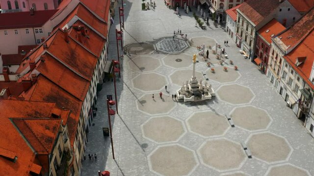 Aerial View Of Few People At Main Square With Plague Column Monument In Slovenia.