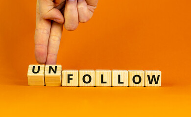 Follow or unfollow symbol. Businessman turns wooden cubes and changes words follow to unfollow. Beautiful orange background, copy space. Business and follow or unfollow concept.