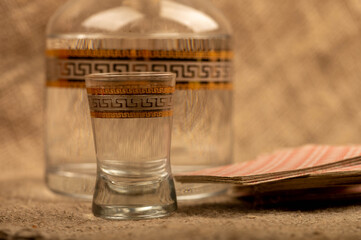 A glass decanter with vodka and a glass of vodka on the background of a homespun fabric with a...