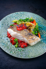 Modern style traditional fried skrei cod fish filet with fennel and tomato cream served as close-up...
