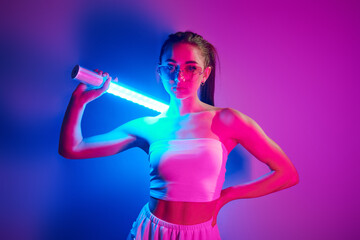 Futuristic style. Fashionable young woman standing in the studio with neon light