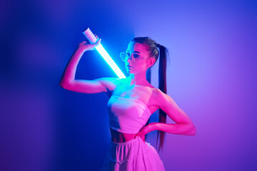 Futuristic style. Fashionable young woman standing in the studio with neon light