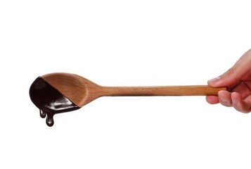Hand holding chocolate cream wood spoon isolated on white background