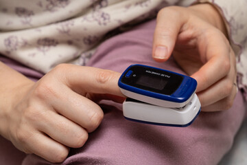 Pulse oximeter used to measure pulse rate and oxygen levels. Female hand with heart rate monitor