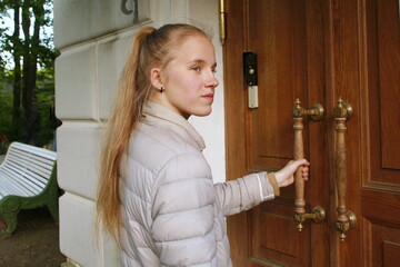 girl opens a wooden door by the handle