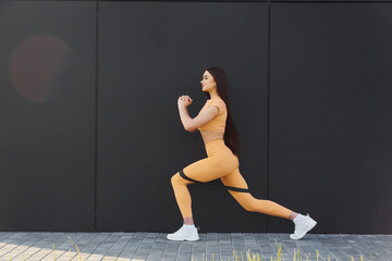 Fitness everyday routine. Young woman in sportswear doing exercises outdoors