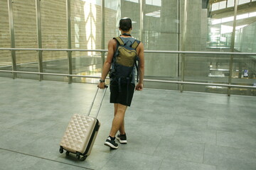 Fototapeta na wymiar guy tourist dragging a suitcase. Active and travel lifestyle concept