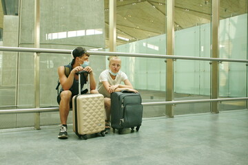 young people with suitcases in their hands are sitting and waiting for the plane