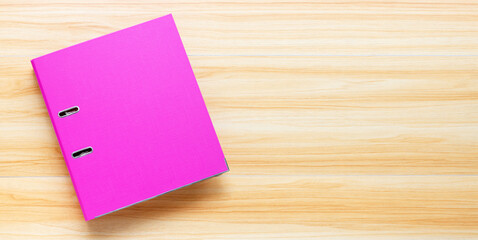 Pink office folder on wooden background. Top view