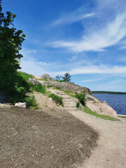A stone staircase on the shore of the Vyborg Bay in the Monrepos Park of the city of Vyborg against the background of a blue sky with clouds..