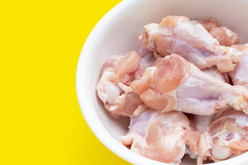 Fresh raw chicken wings (wingstick) in white bowl on yellow background.