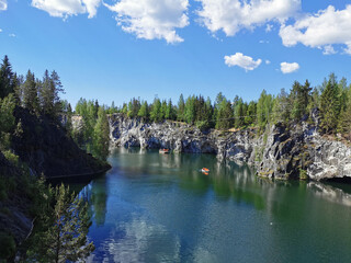 View from the observation deck of the emerald water of the Marble Canyon in the Ruskeala Mountain Park with the reflection of the sky and clouds on a sunny summer day.