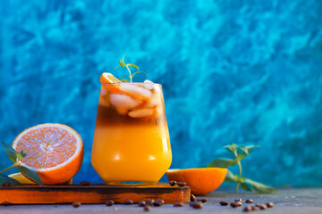 Refreshing summer iced coffee cocktail. Espresso coffee, orange juice, rosemary and cinnamon. Bumble coffee. Blue creative background