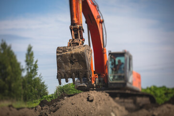 Yellow heavy excavator and bulldozer excavating sand and working during road works, unloading sand during construction of the new road