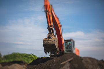 Yellow heavy excavator and bulldozer excavating sand and working during road works, unloading sand during construction of the new road