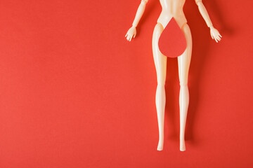 doll with a paper drop of blood on the thighs, feminism art, women's health and gnecology concept, menstruation