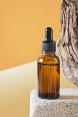 brown glass bottle with a pipette on a concrete podium on a wooden driftwood background, brown background