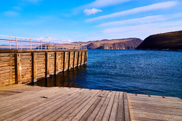 An old wooden pier on a sunny day with blue water and sky