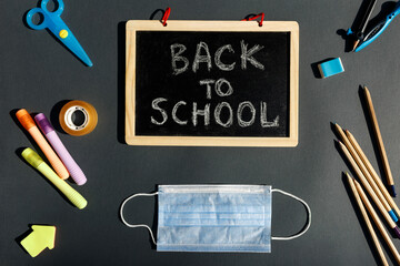 E- learning,Online education, School stationery supplies, medical mask, social distancing, school reopening. Back to school after covid-19 pandemic. New normal concept.Top view copy space,blackboard.