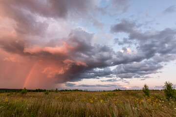 Obraz na płótnie Canvas Storm clouds with a rainbow before sunset