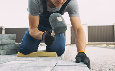 Worker lining paving slabs path