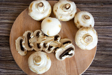 Champignons top view. Champignon mushrooms lie on a wooden cutting board. Chopped edible mushrooms.
