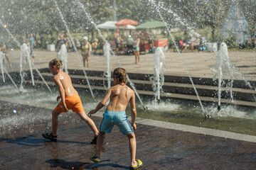 boys running and playing in city fountain on hot summer day, Saint-petersburg, Russia