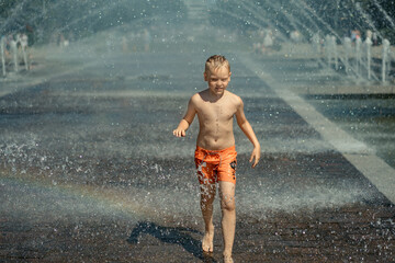 Fototapeta na wymiar cute caucasian boy wearing swimming shorts running in a fointain