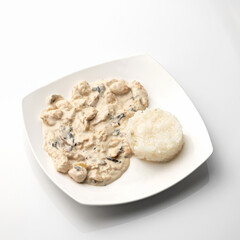 Rice with mushrooms in sour cream sauce. Plate of food isolated on white background.