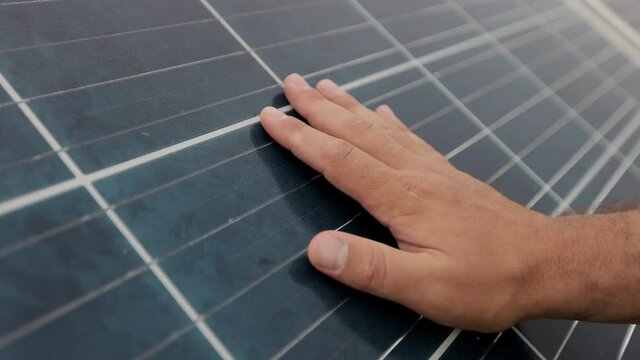 Close up of a young man engineer hand is checking the operation of sun and cleanliness of photovoltaic solar panels. Concept for ecology. Solar farm. Clean energy concept.