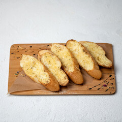 Croutons with garlic sauce on wooden cutting board. Fried bread on white background.
