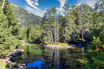Fototapeta na wymiar Scenic view of waterfall and lake in a Spanish Pyrenees Mountain in a sunny day. Transparent clear water.Aiguestortes i Estany of Saint Maurici National Park
